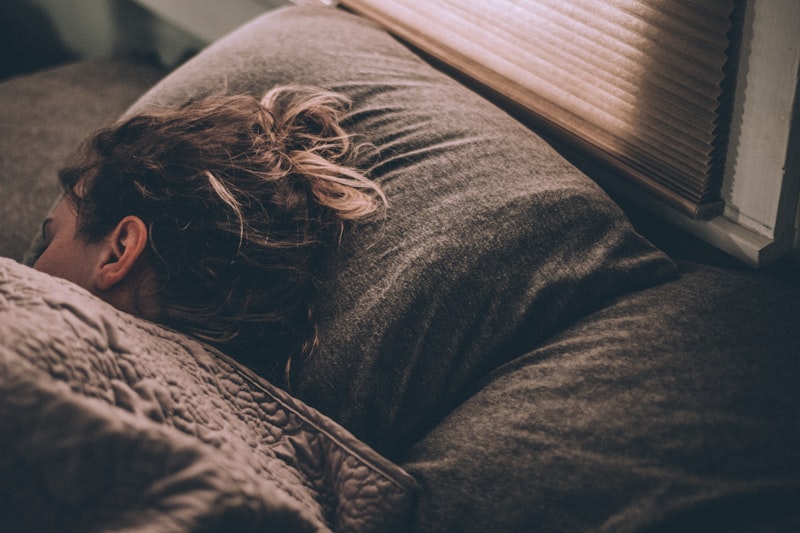 Woman resting under cozy blanket - deep restorative sleep cycle for better REM sleep